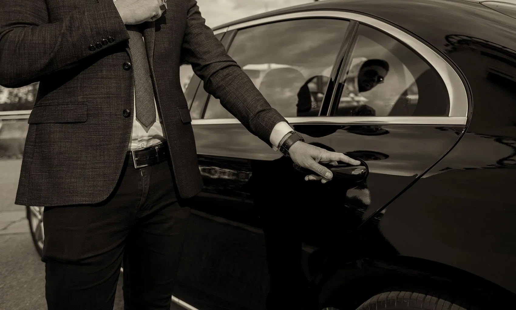 A chauffeur opening the door of a luxury sedan